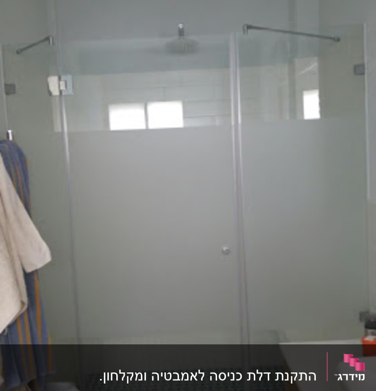 מקלחון זכוכית עם מגבות תלויים בצד